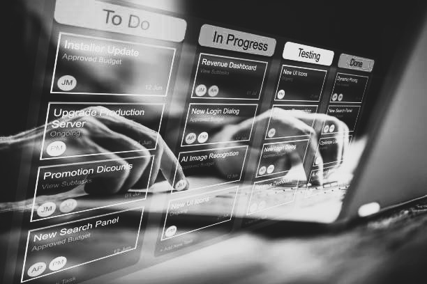 Schwarzweiss bild mit den Prozessen des Projektmanagements und 2 Hönden am Laptop